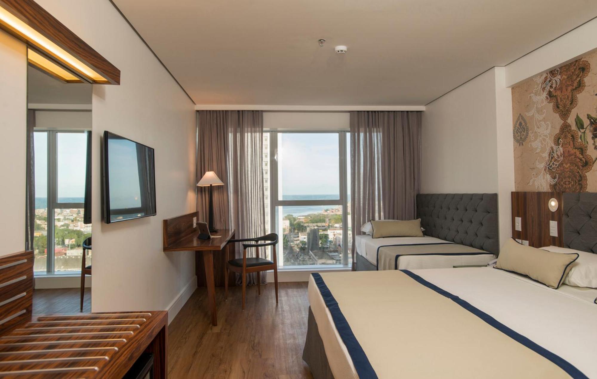 Hotel Luzeiros Recife Kültér fotó The photo shows a hotel room that features a modern and comfortable design. There are two beds: one larger bed and a smaller twin bed. The room has large windows with curtains that allow natural light to enter, offering a view of the outside, possibl